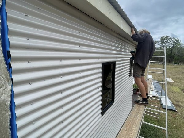 Fixing new corrugated iron cladding sheet by sheet along a gable wall
